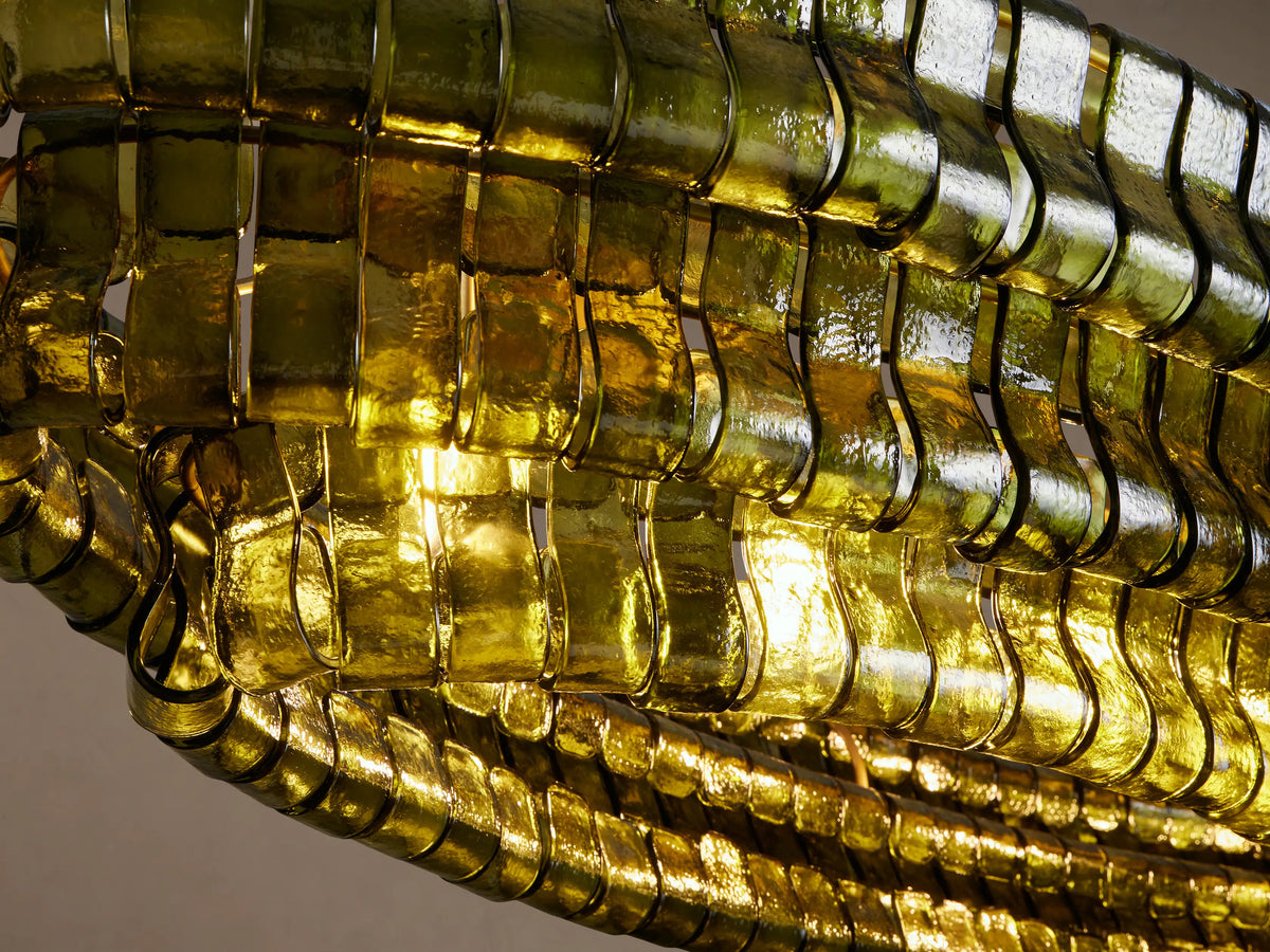 Ghiaccio Oval Chandelier with layered dark green curved glass tiles, suspended by two black chains against a beige wall.