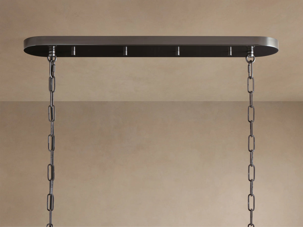 Close-up of Ghiaccio Oval Chandelier. Curved, textured olive green glass panels glow warmly, arranged in overlapping rows.