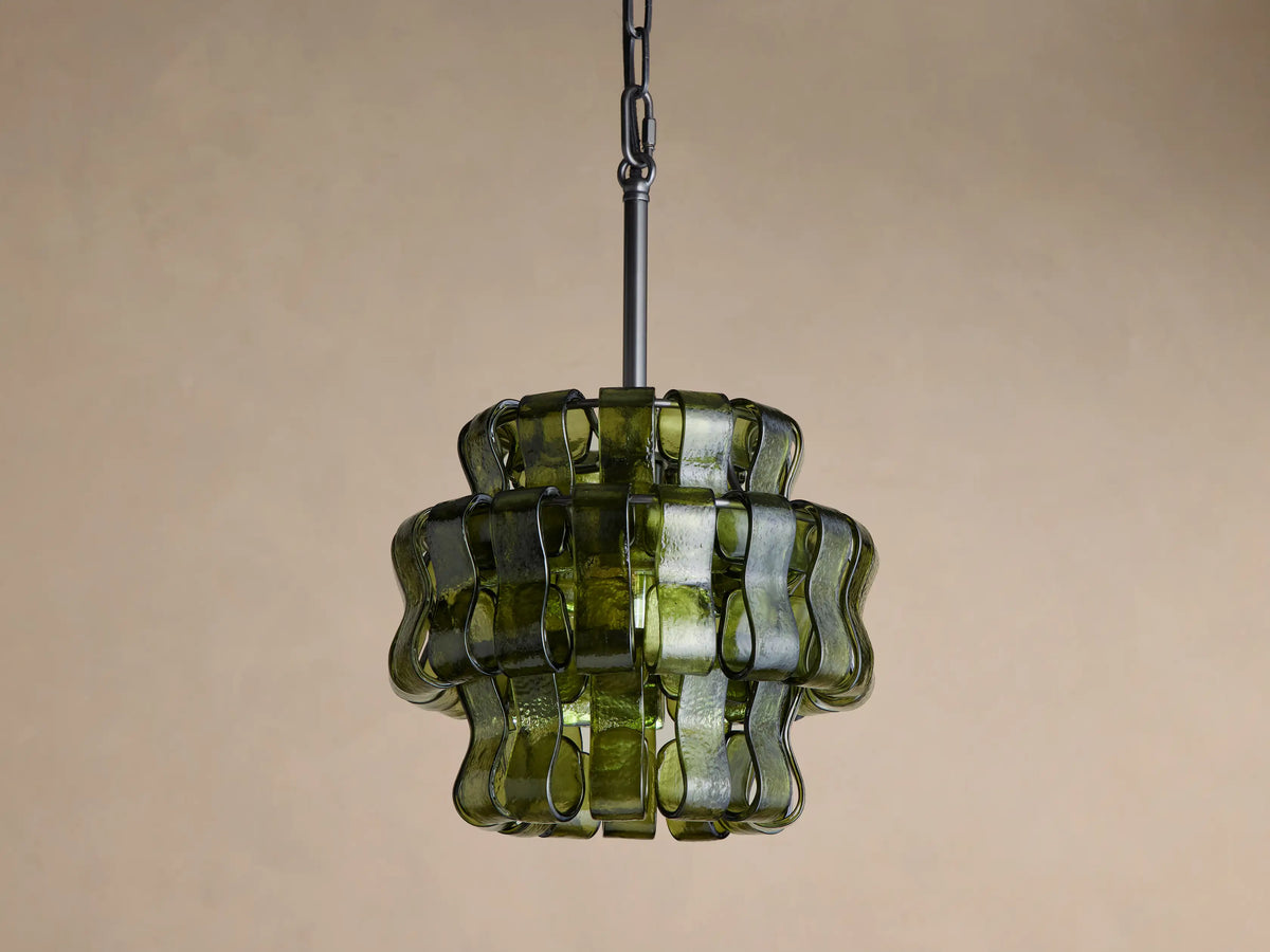Ghiaccio Pendant: Dark green wavy curved glass pieces around a warm yellow glow, hanging from a black chain against a dark background.