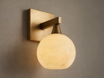 Front view of a brass wall light with a square backplate, horizontal arm, and glowing, translucent white veined globe shade.