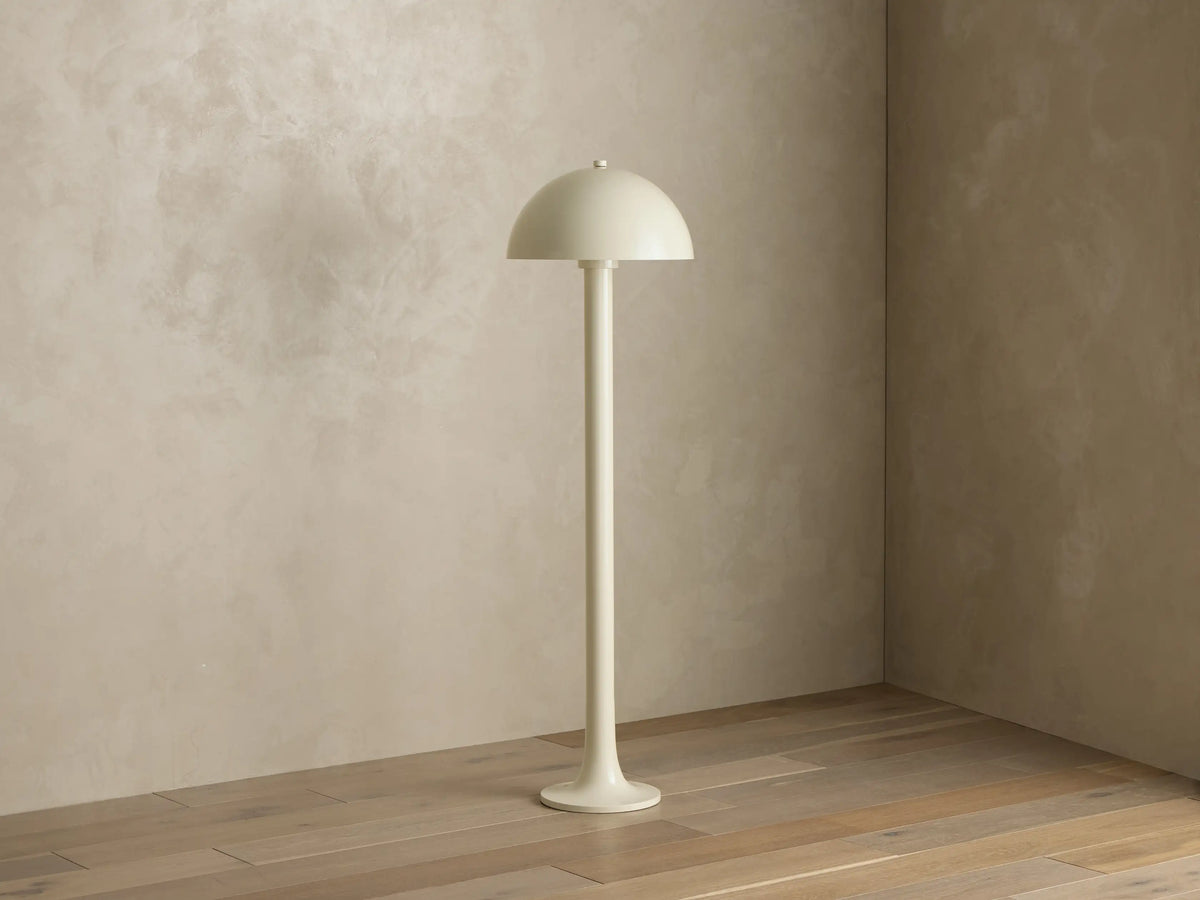 Front view of a light beige Floor Lamp with a mushroom-shaped shade, standing on a wooden floor and casting warm light.