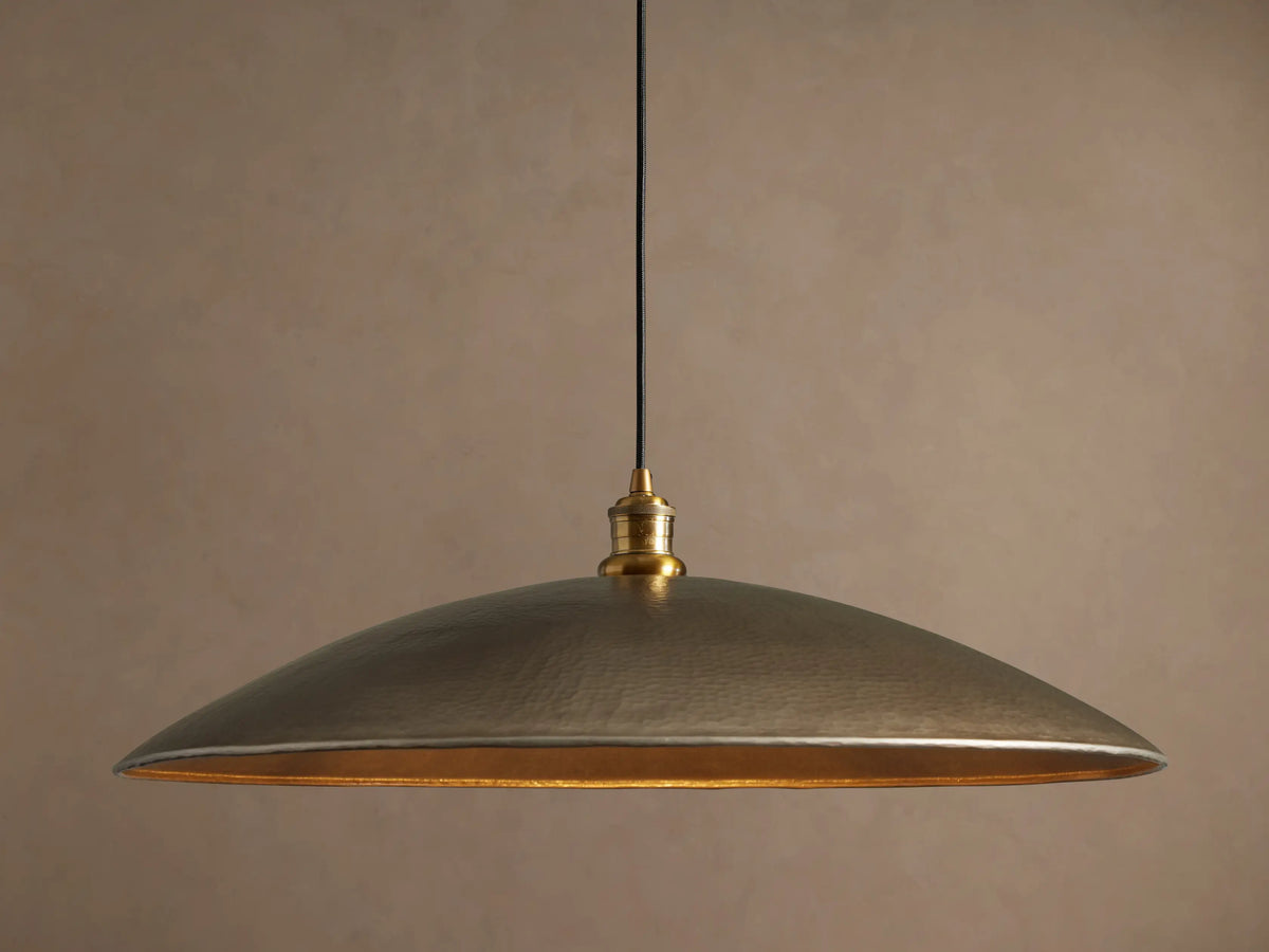Recycled Metal Fan Pendant with wide, hammered brass-finished shade and reflective golden interior, hanging from a black cord.