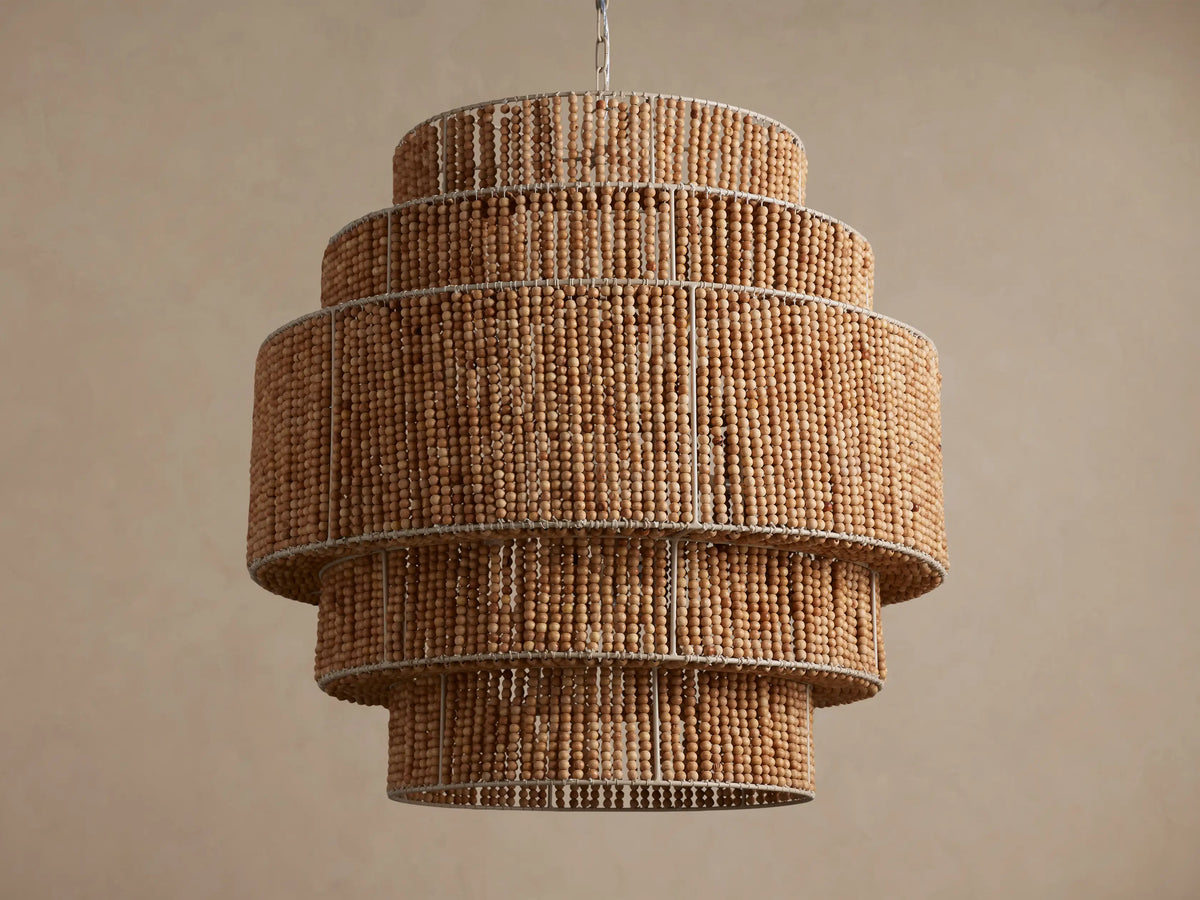 Kash Chandelier, a layered, cylindrical light fixture made of natural wooden beads, with warm internal lights glowing.