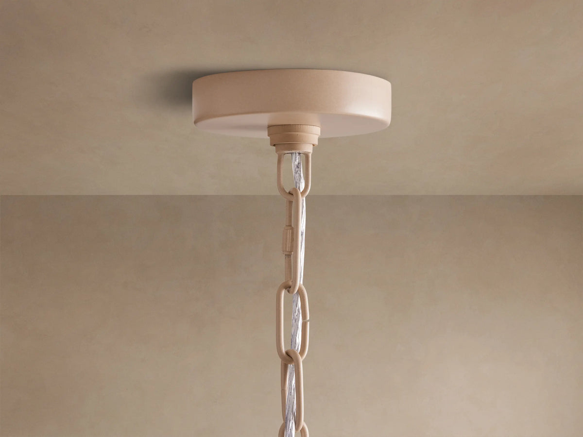Kash Chandelier: Close-up, bottom-up view of multiple tiers of warm, light brown wooden beads strung on an ivory metal frame, glowing brightly.