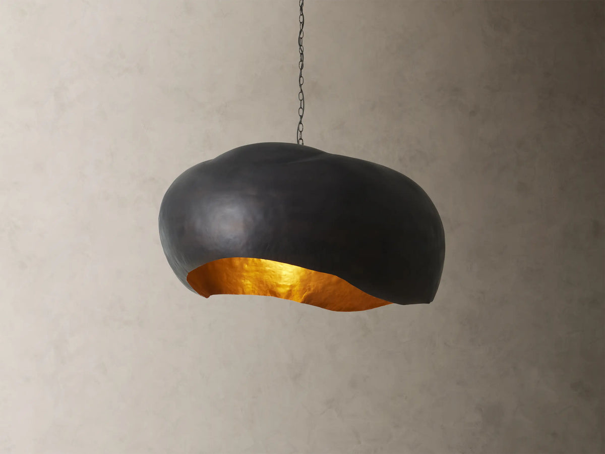 Front view of the black Fria Dome Pendant, an organically shaped light with a textured gold interior.