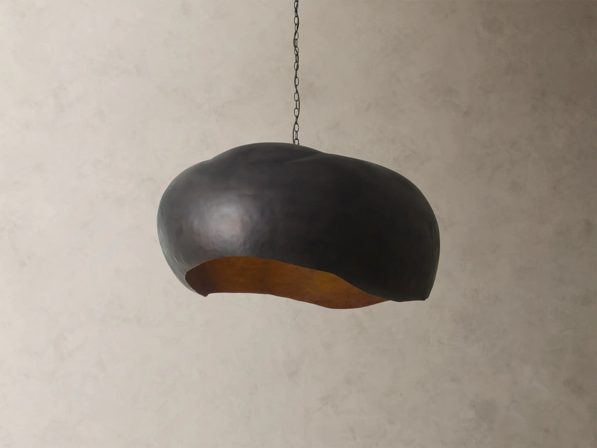 Front view of the black Fria Dome Pendant, an organically shaped light with a textured gold interior.