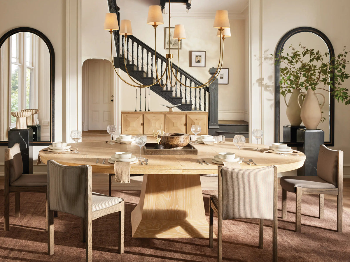 Saige Round Chandelier with a bronze finish, six illuminated off-white tapered fabric shades, hanging against a dark background.