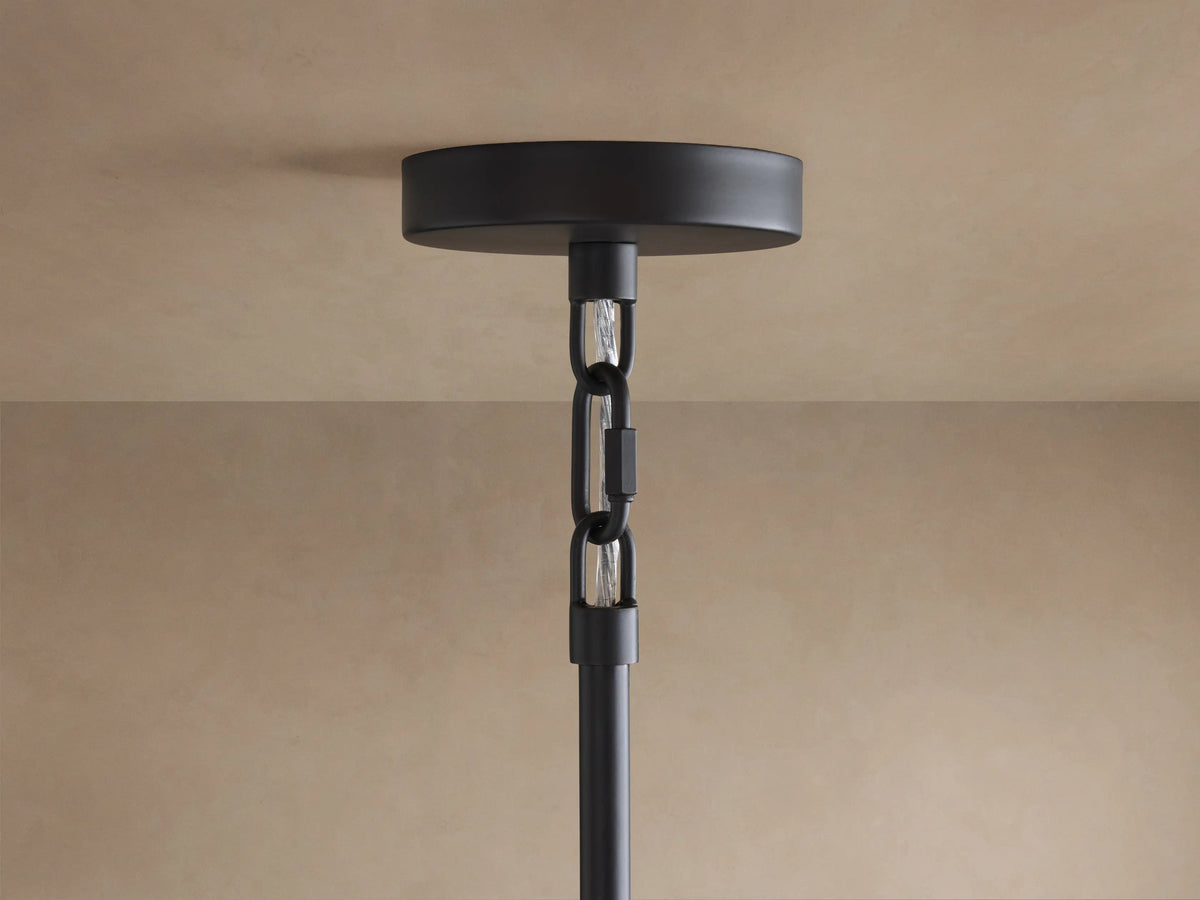 Black ceiling canopy of Saige Round Chandelier attached to a beige ceiling, with a black rod and chain extending down.