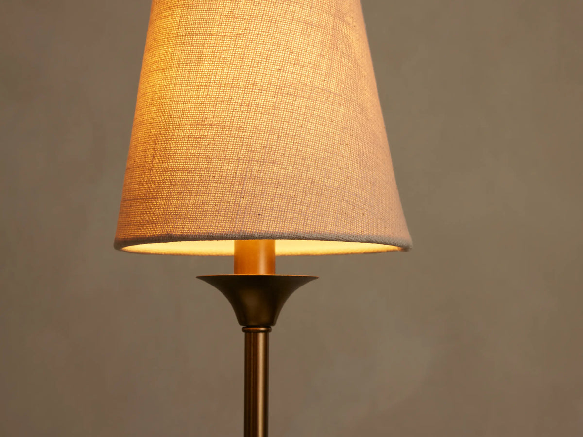 Close-up of a lit Saige Round Chandelier's off-white textured shade, brass-toned stem, emitting a warm light.