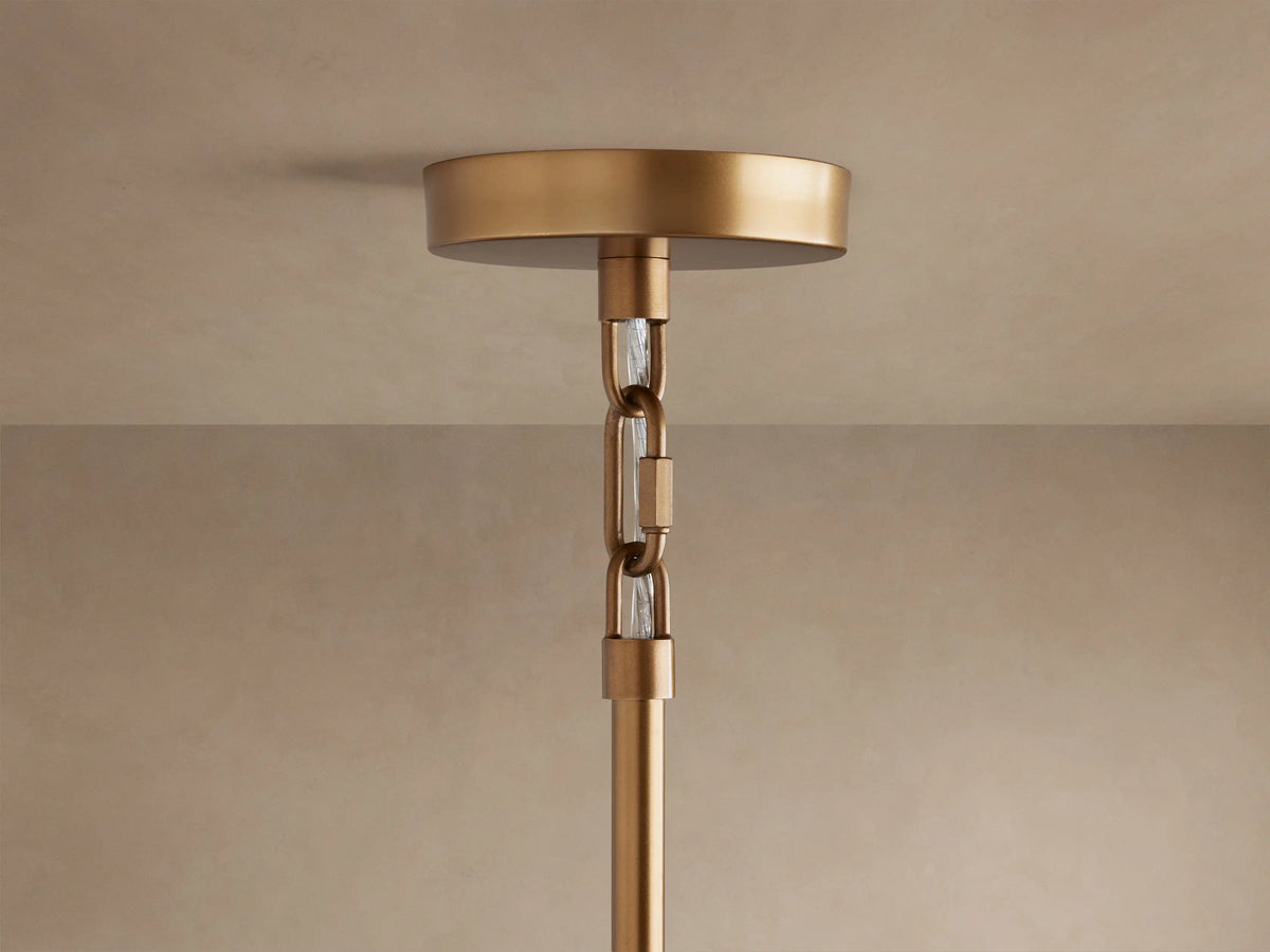 Saige Round Chandelier's brass ceiling canopy connected to a descending extension rod by two chain links with clear glass inserts.