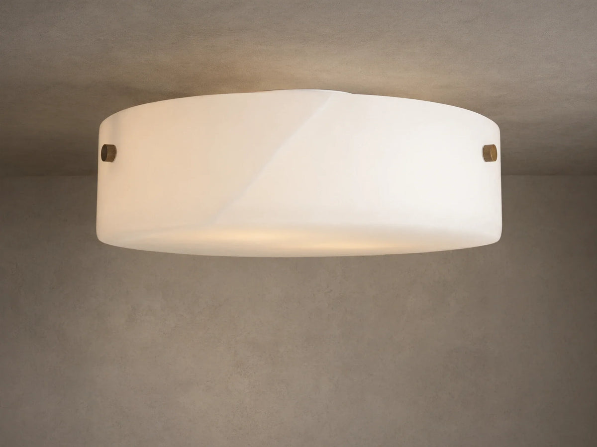 The Chayla Flushmount features a round alabaster shade with metal accents on a ceiling, casting soft ambient light.