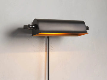 Tremont Bronze Library Sconce with a dark bronze finish, rectangular shade, mounted on a wall, illuminated warm light.
