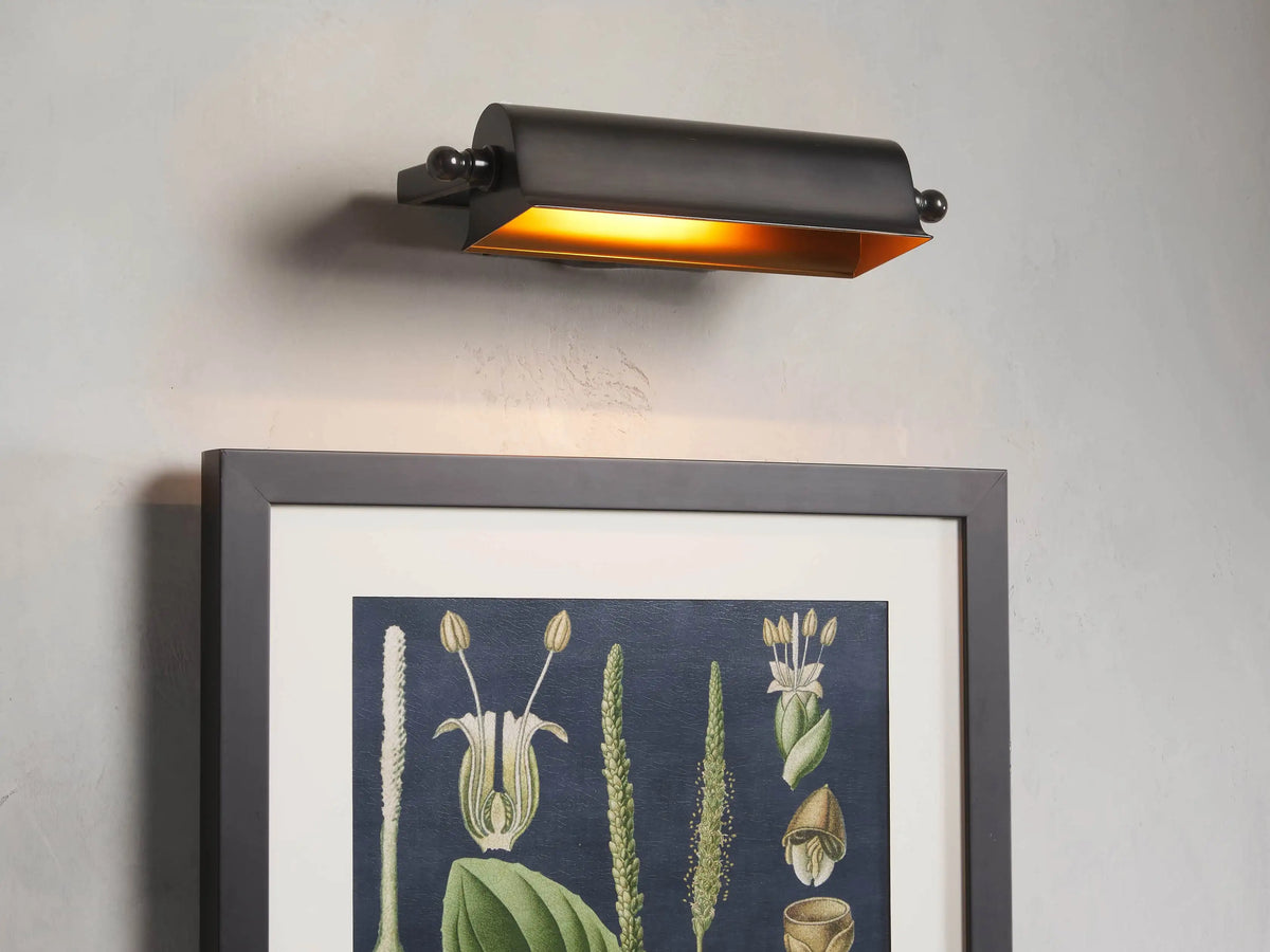 Tremont Bronze Library Sconce with a dark bronze finish, rectangular shade, mounted on a wall, illuminated warm light.