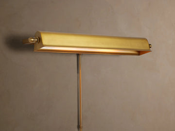 Antiqued metallic Tremont Picture Light Sconce on a textured wall, glowing warmly downwards.