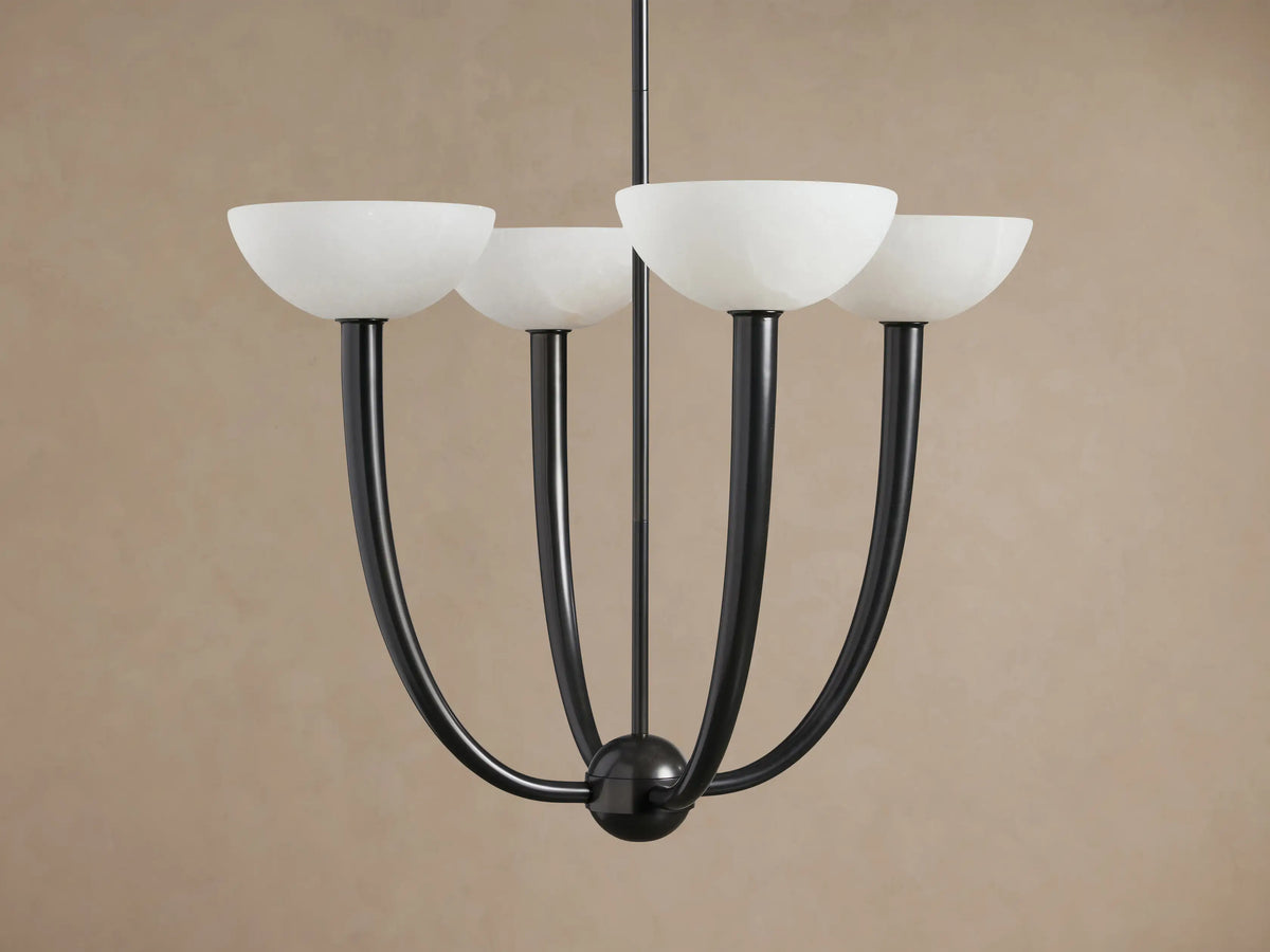 Saguaro Chandelier with four glowing white alabaster bowl shades on dark, upward-curving arms against a brown wall.