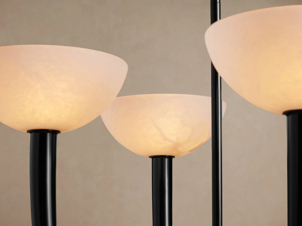 Saguaro Chandelier with four upward-facing white alabaster bowl shades supported by dark curved iron arms, against a beige wall.