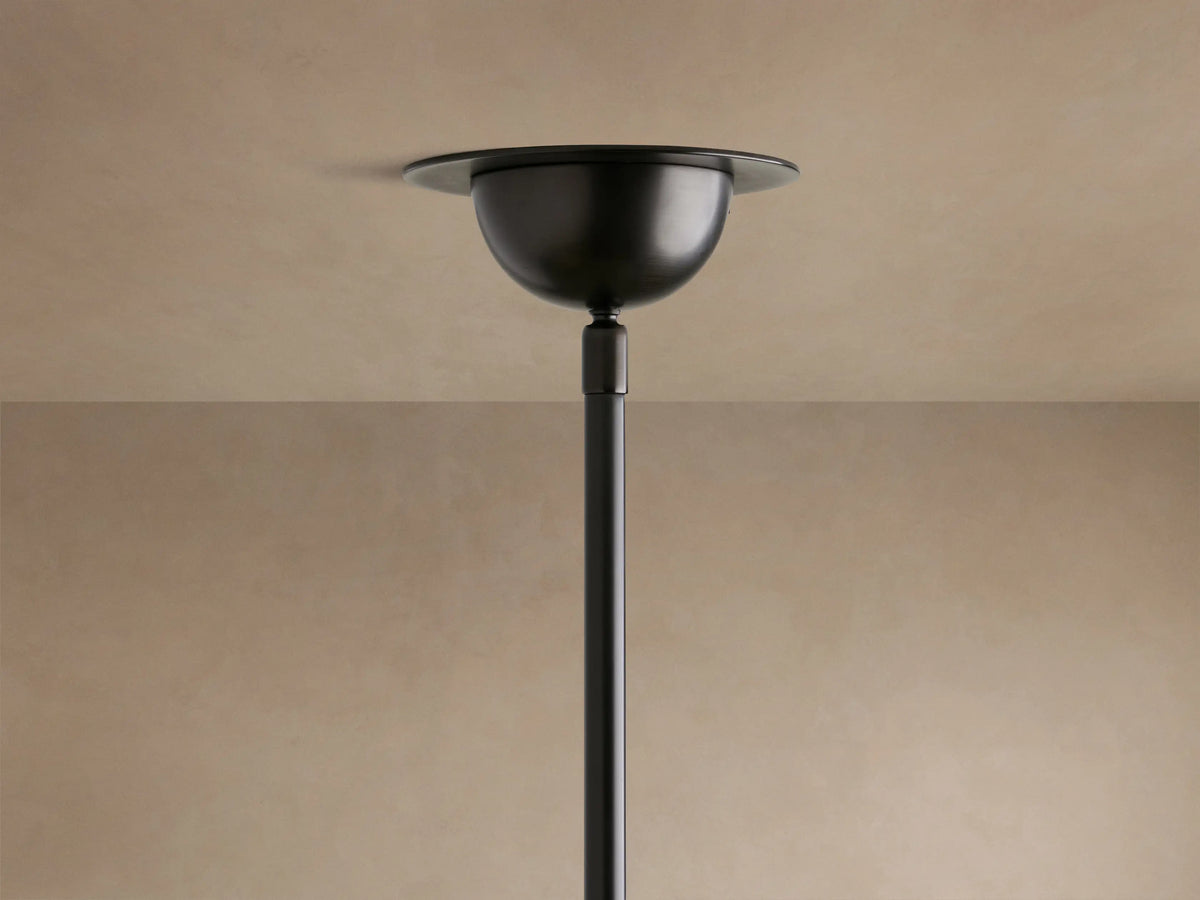 Close-up of a Saguaro Chandelier showing three glowing, bowl-shaped alabaster shades on black metal arms, emitting warm light.
