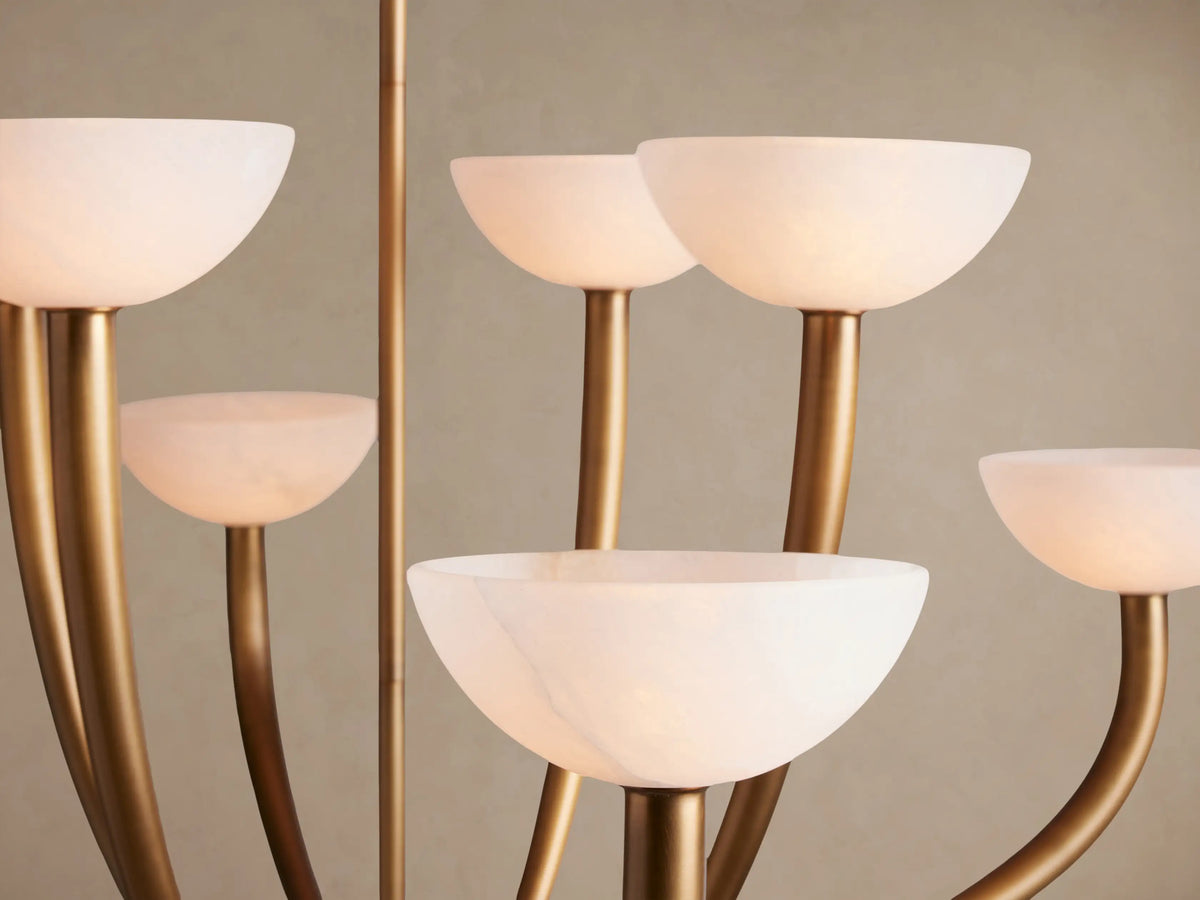 Saguaro Chandelier: Antique brass finish with eight white alabaster bowl-shaped shades, against a plain beige wall.