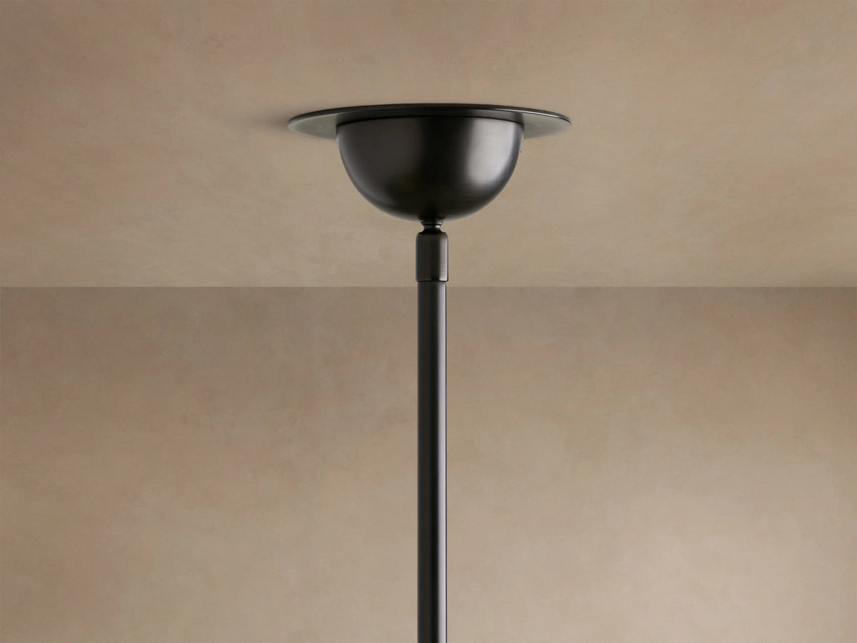 Close-up of Saguaro Chandelier with multiple glowing, natural alabaster bowl shades on dark, curved iron arms against a beige wall.