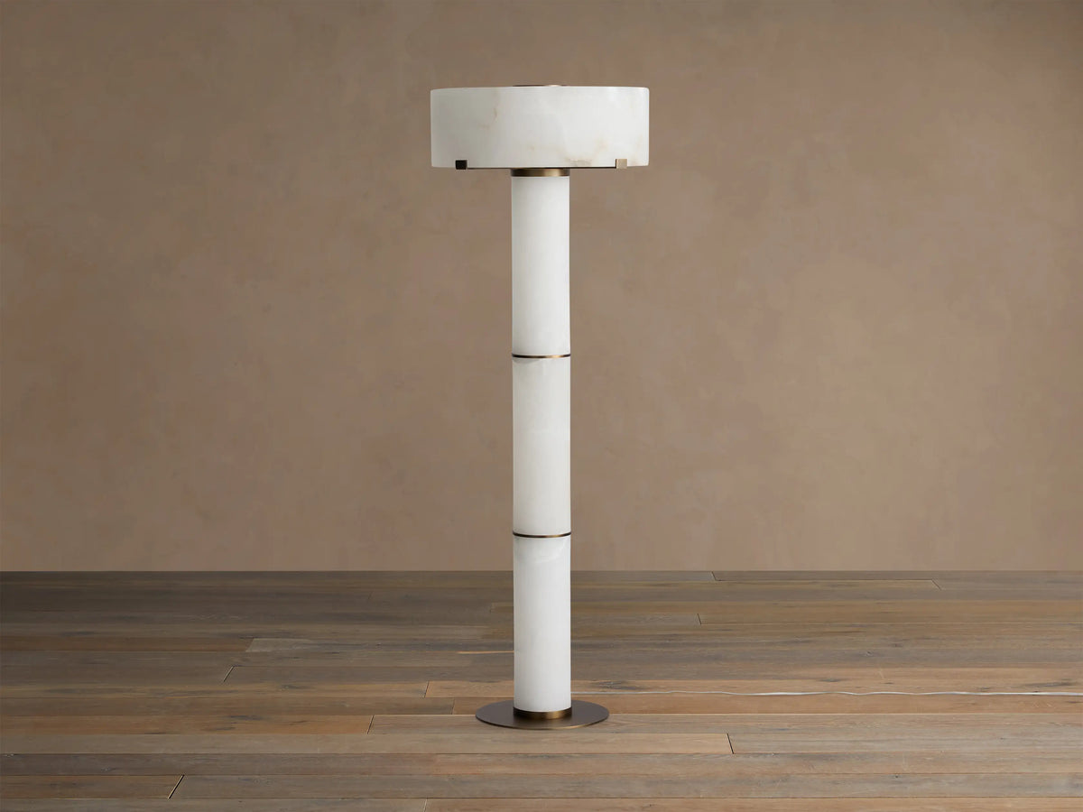 Chayla Floor Lamp: tall, cylindrical white alabaster lamp with natural patterns, bronze accents, on a wood floor.
