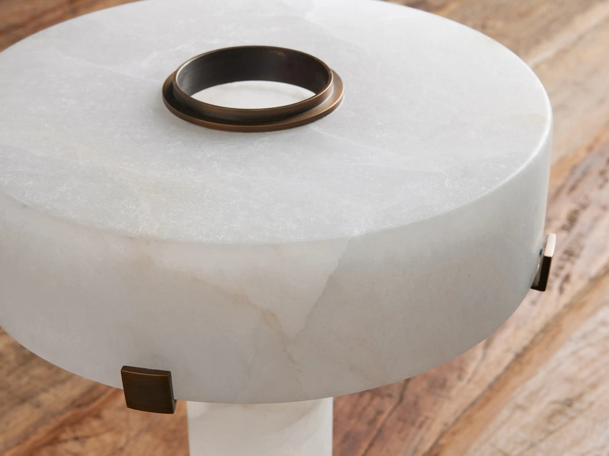 Close-up of Chayla Table Lamp's round white alabaster top with antique brass ring & small metallic side accents on wood.