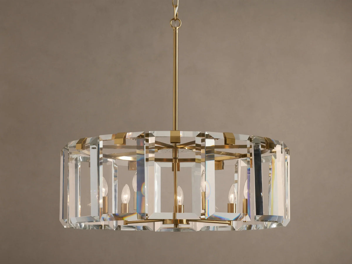 Round Amaya Chandelier with brass frame & thick, clear crystal panels, showcasing five candelabra bulbs, against a plain wall.