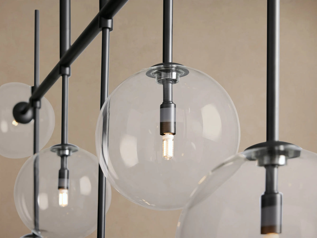 Roscoe Linear Chandelier with a black linear frame and seven clear glass globes, some facing up, some down, against a beige wall.