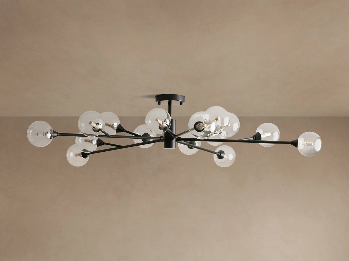 Apollo Flush Mount with dark arms, 12 clear glass globe bulbs emitting warm light against a beige ceiling.