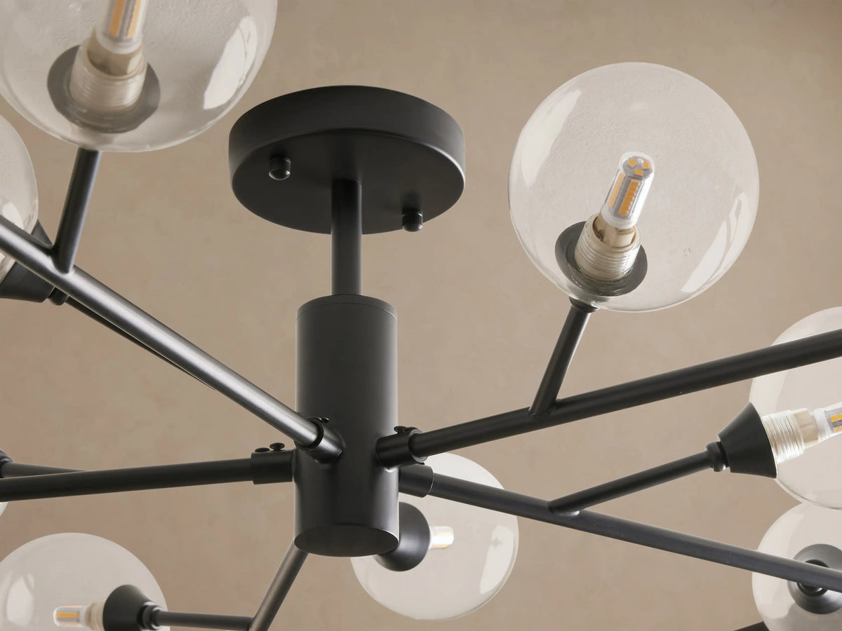 Apollo Flush Mount: Black modern sputnik-style ceiling light with clear globe bulbs on radiating arms, mounted on a brown ceiling.