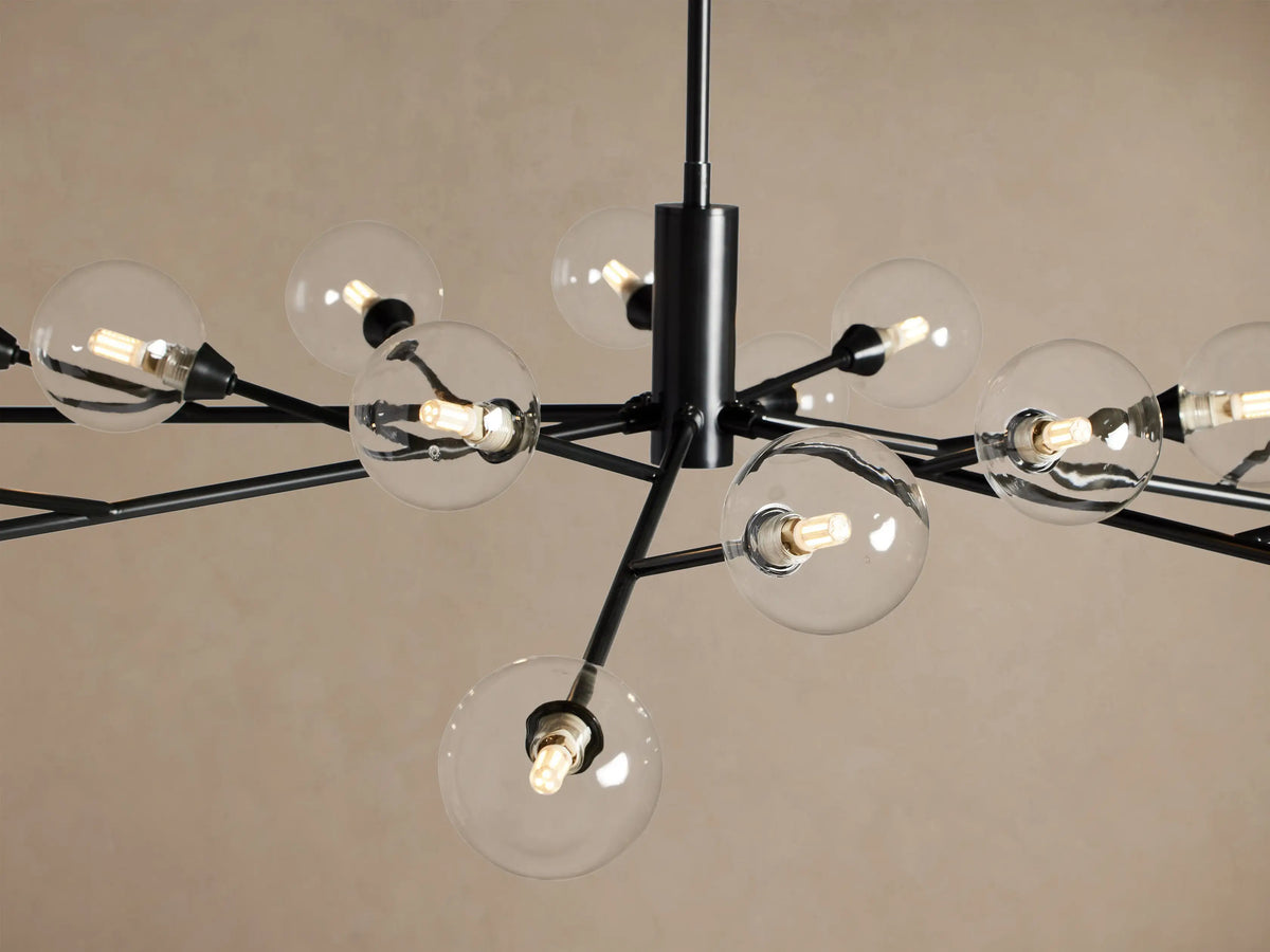 Apollo Round Chandelier: 18 clear globe bulbs on black metal arms radiate from a central stem, against a beige wall.