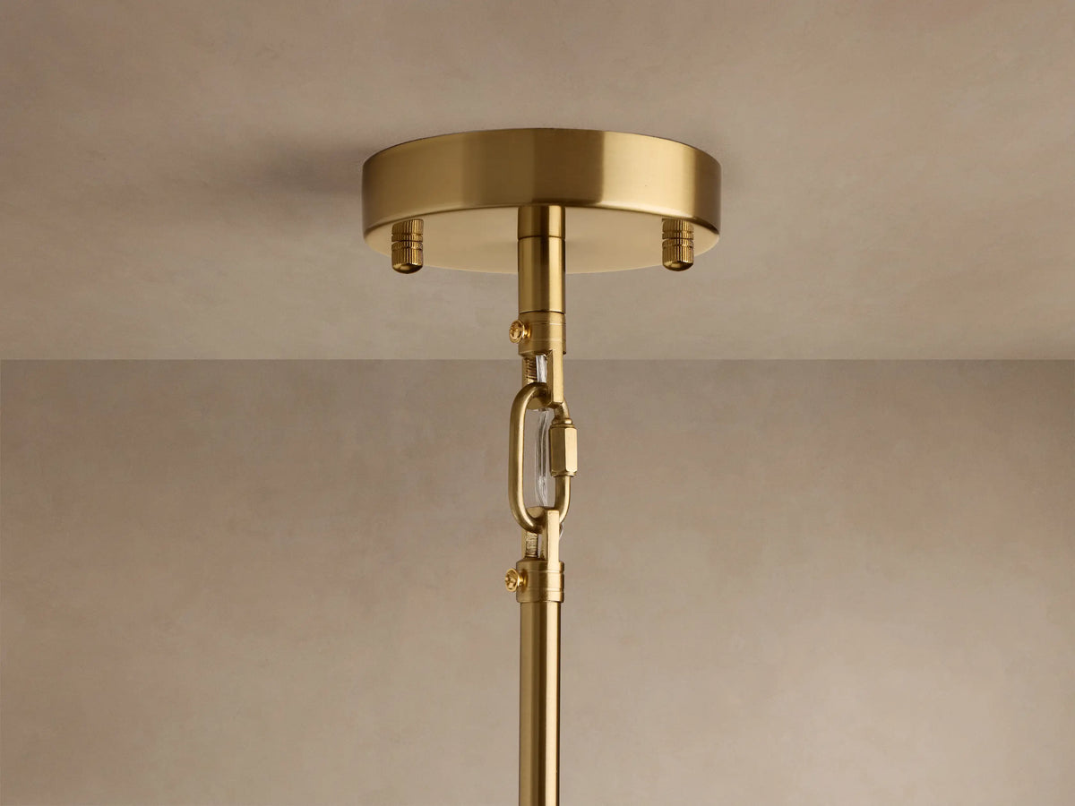 Close-up of Apollo Round Chandelier with polished brass arms radiating from center, holding clear spherical glass shades with glowing bulbs.