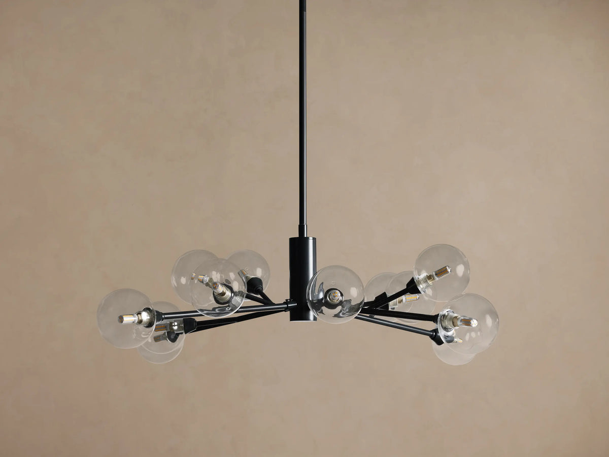 Apollo Round Chandelier: Black iron arms holding clear glass globes with illuminated bulbs, suspended on a tan background.
