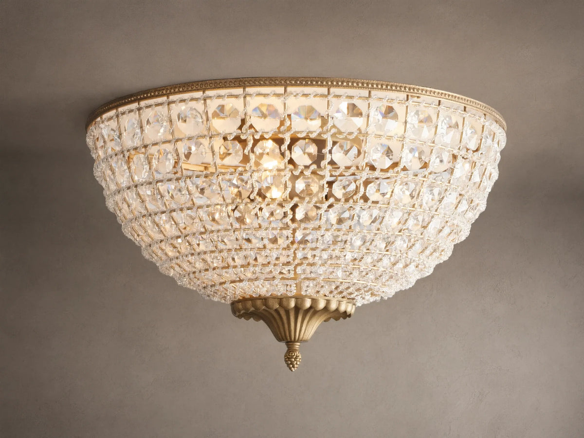 Poppy Flush Mount. Dome-shaped fixture with rows of clear faceted crystals and antique brass accents, glowing warmly on a ceiling.