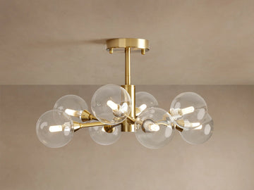 Apollo Flush Mount with 8 illuminated clear globe bulbs on a polished brass frame, mounted flush against a beige ceiling.