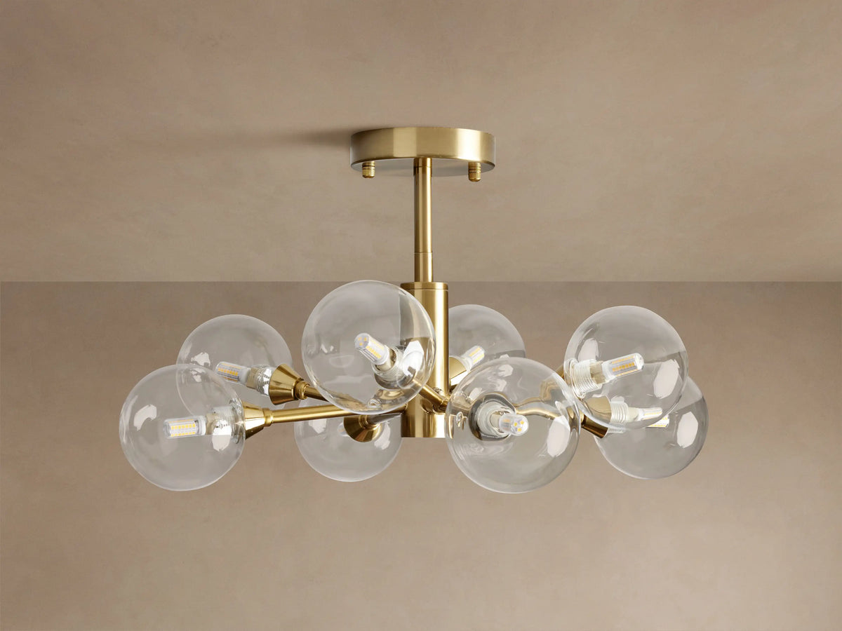 Apollo Flush Mount with 8 illuminated clear globe bulbs on a polished brass frame, mounted flush against a beige ceiling.
