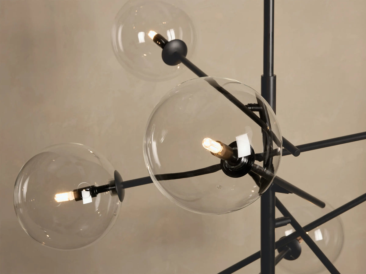 Close-up of Roscoe Chandelier with multiple clear glass globes and illuminated bulbs on a dark bronze iron frame.