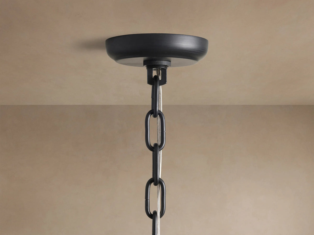 Close-up of Amaya Round Chandelier's black canopy and chain with clear wire, mounted on a light brown ceiling.