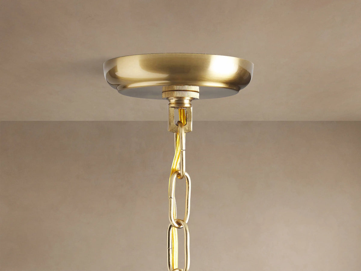 Close-up of Lily Round Chandelier. Clear glass petals and golden rods radiate from a central brass sphere with small bulbs.