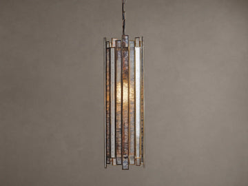 Laila Pendant, a cylindrical light with vertical antiqued mirrored-glass panels and an antique copper frame, glowing warmly.