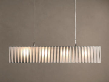 Horizontal Jeunet Rectangular Chandelier in Nickel, hanging against a tan wall, showing glowing white panels through vertical nickel bars.