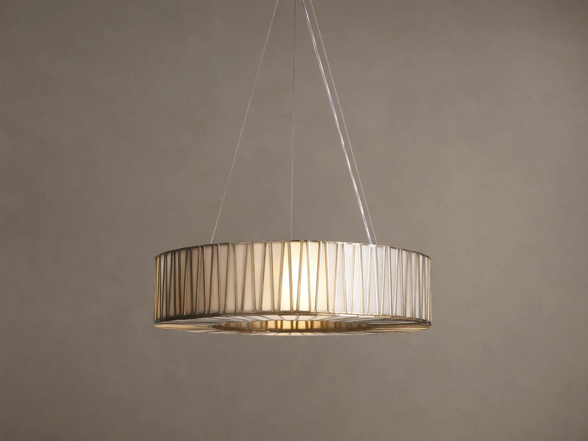 Jeunet Round Chandelier with antiqued brass geometric frame, illuminated cream glass panels, hanging from cables on a warm wall.