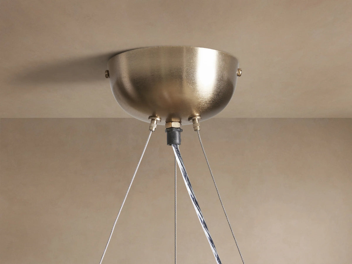 Close-up of a glowing Jeunet Round Chandelier with a round brass frame and illuminated rectangular glass panels.