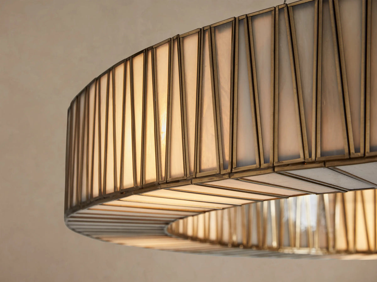 Jeunet Round Chandelier, a large circular fixture with vertical fluted glass panels framed in antiqued brass, suspended by thin wires.
