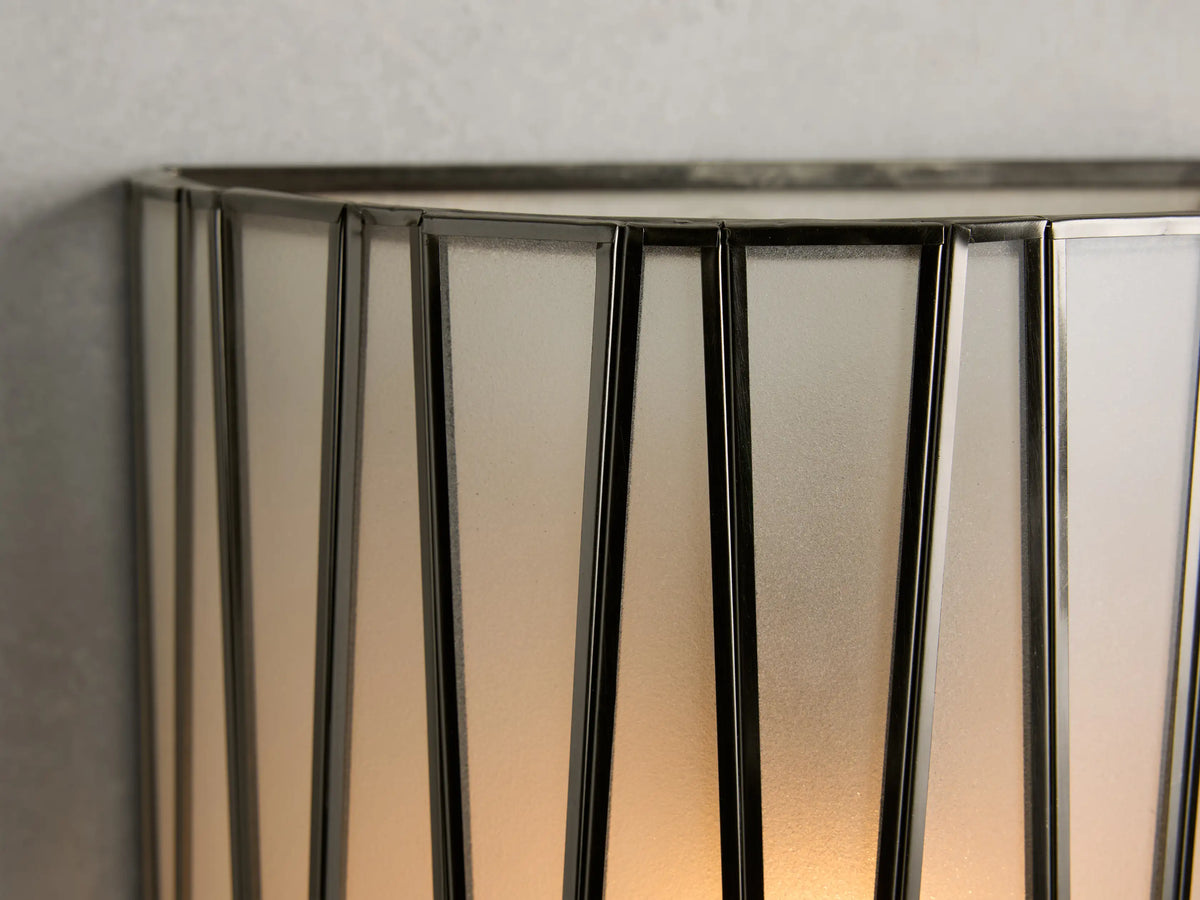 Jeunet Sconce with a cylindrical shape, featuring a glass and iron design in antiqued brass finish. Geometric patterns on glass.