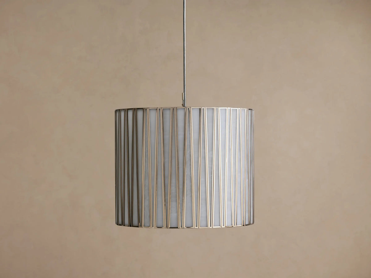 Hanging Jeunet Pendant light, cylindrical white shade with vertical antiqued nickel metal strips, softly glowing.