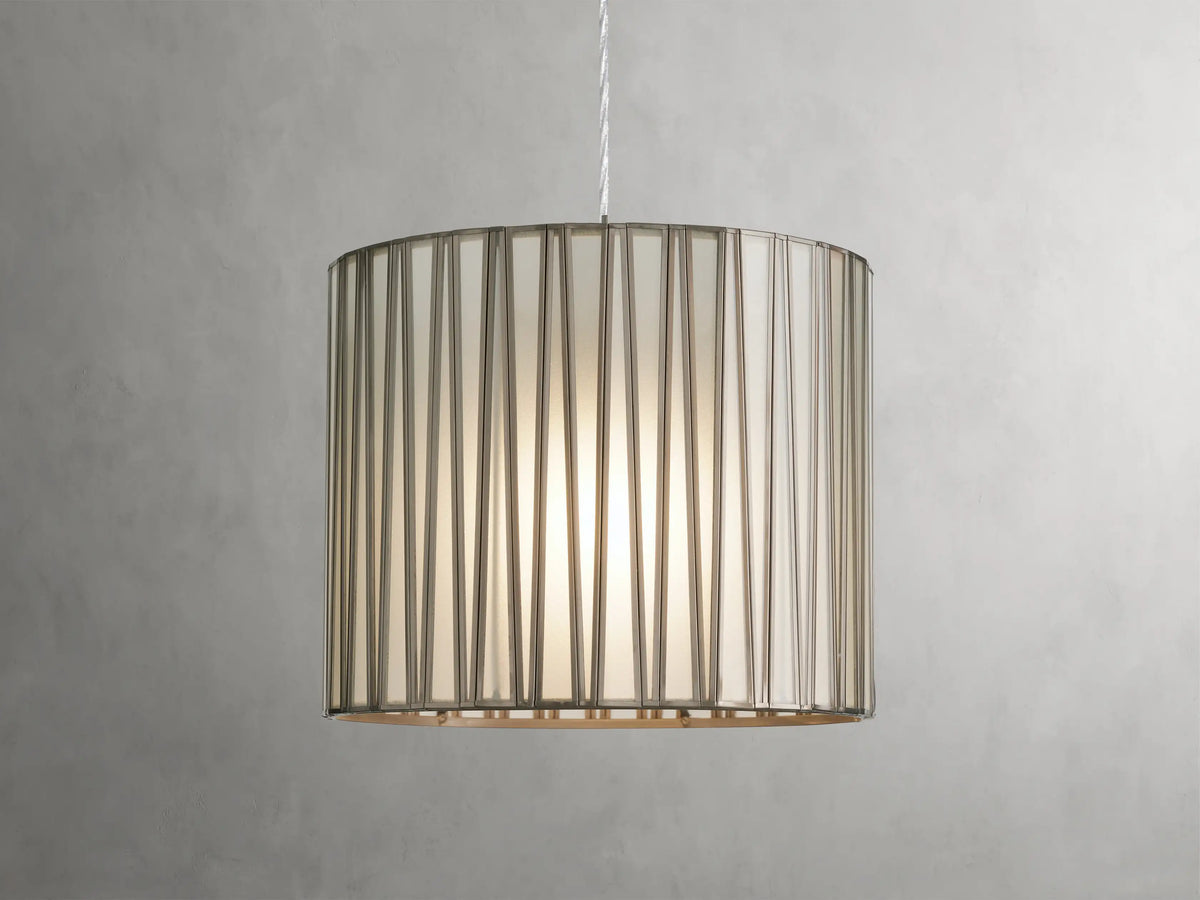 Jeunet Pendant with antiqued brass finish, cylindrical glass and iron shade, emitting soft light, suspended by a clear cord.