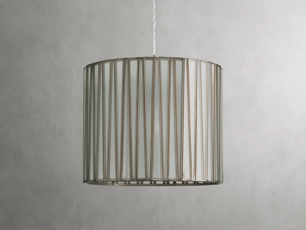 Jeunet Pendant with antiqued brass finish, cylindrical glass and iron shade, emitting soft light, suspended by a clear cord.