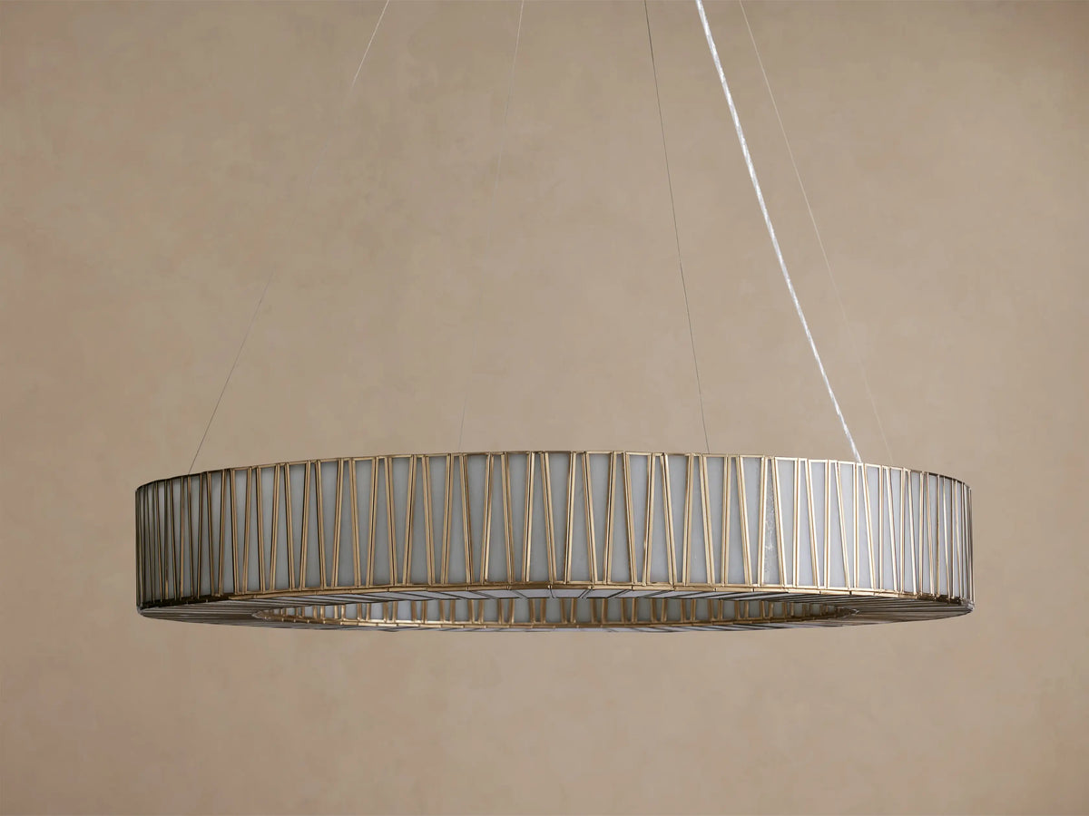 Jeunet Round Chandelier with an antiqued brass geometric frame and glowing white inner diffuser, suspended by thin cables.