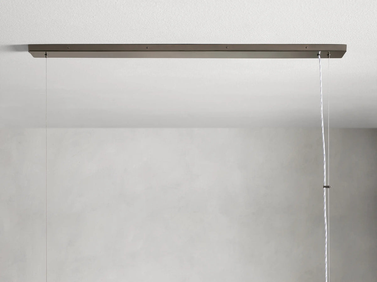 Rectangular chandelier with vertical glass panels and an iron frame. Features a warm glow from interior bulbs, suspended by a cable.