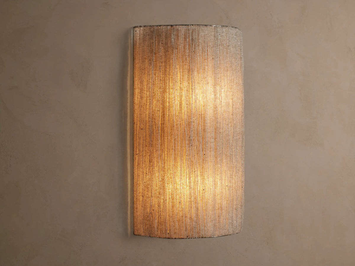 Romilly Beaded Sconce, vertical, elongated, warm light shining through its textured, light-colored strung glass beads on a neutral wall.